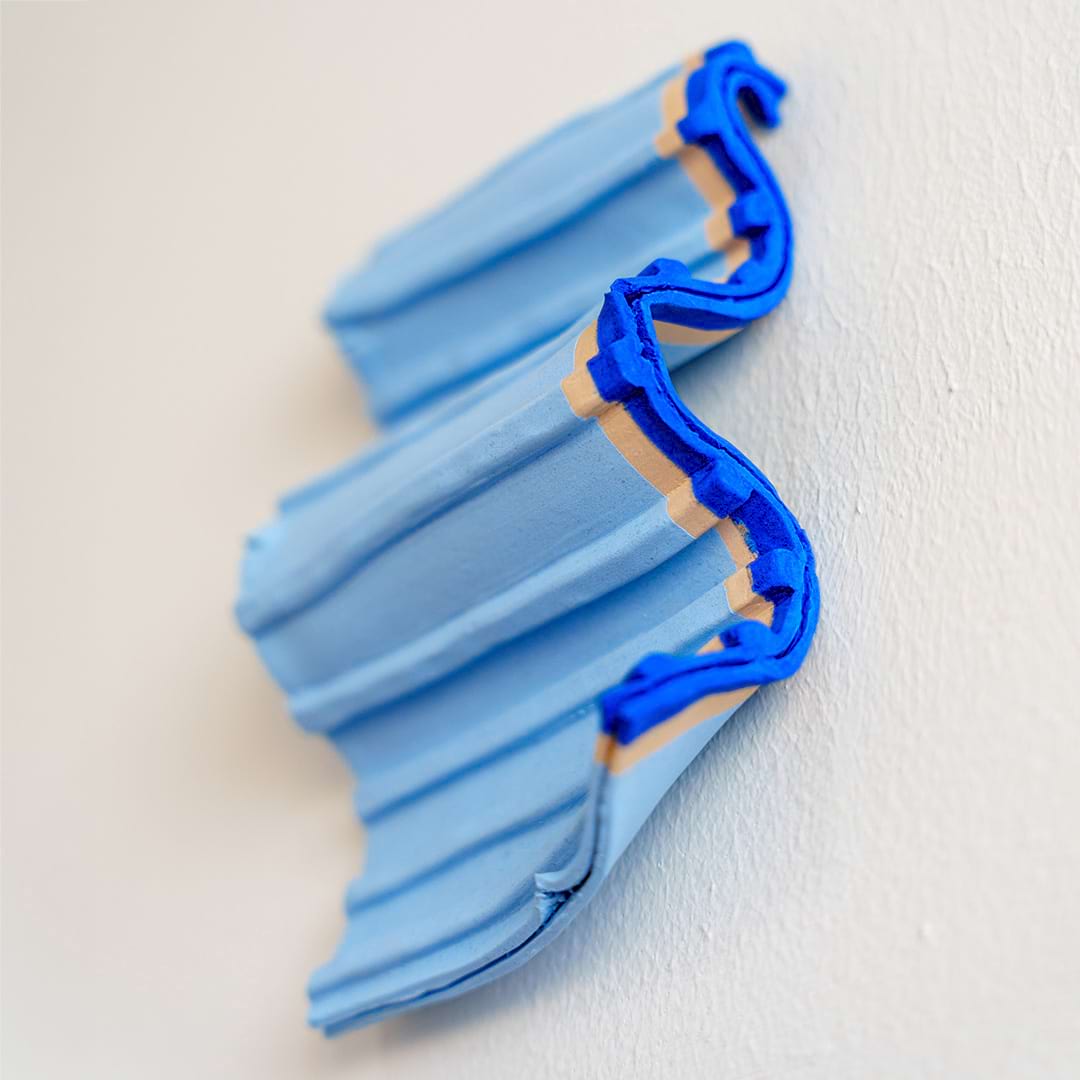 Foto van een blauw keramiekobject aan de muur in de vorm van een golf