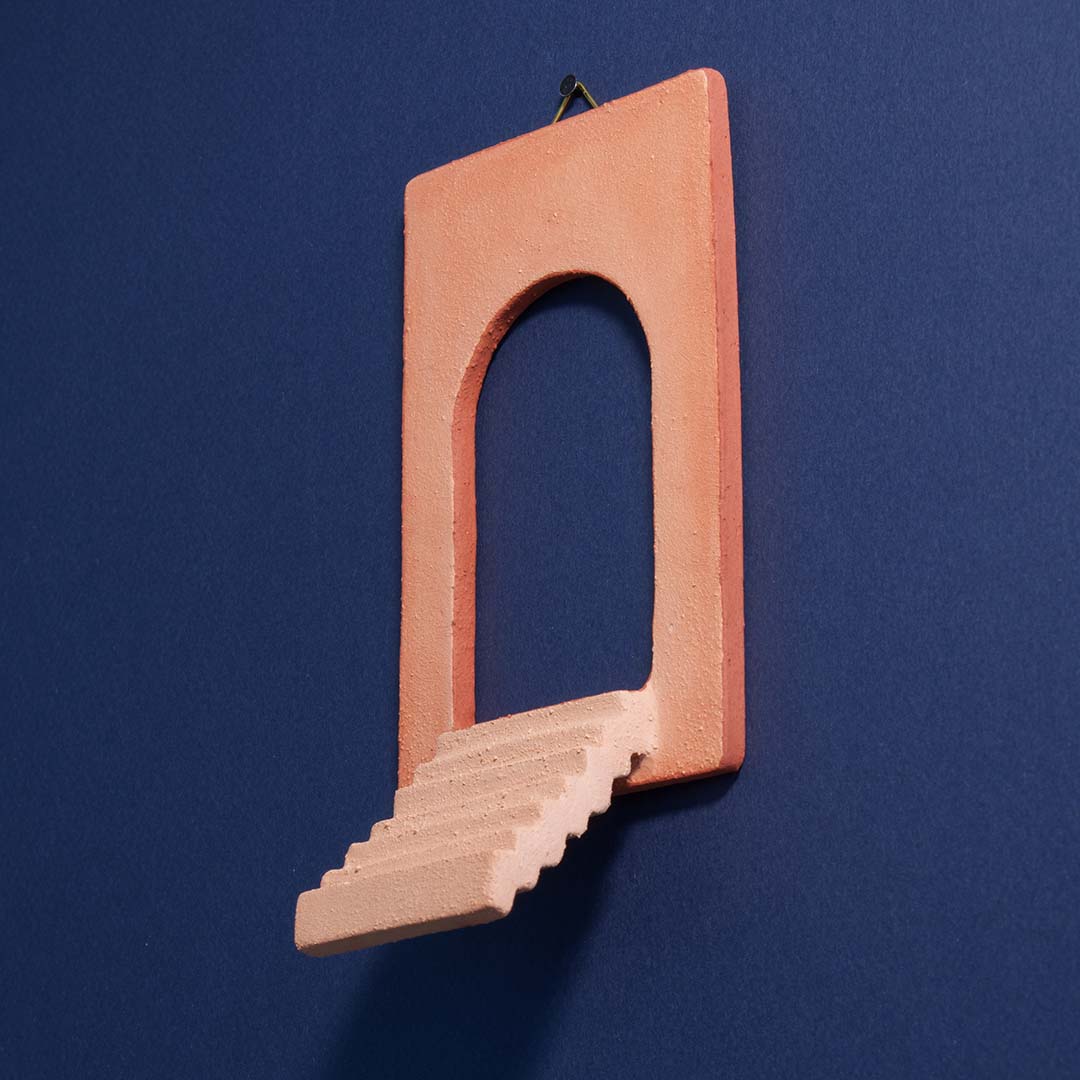 Foto van een kunstwerkje aan de muur van een trapje met een open poort