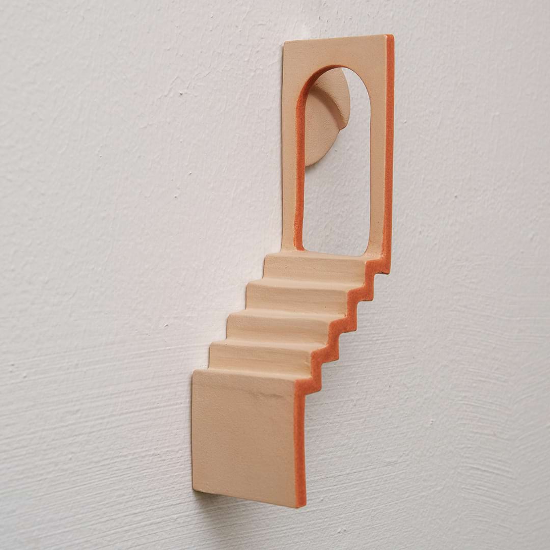 Foto van een werk van keramiek aan de muur met een trapje en een poort
